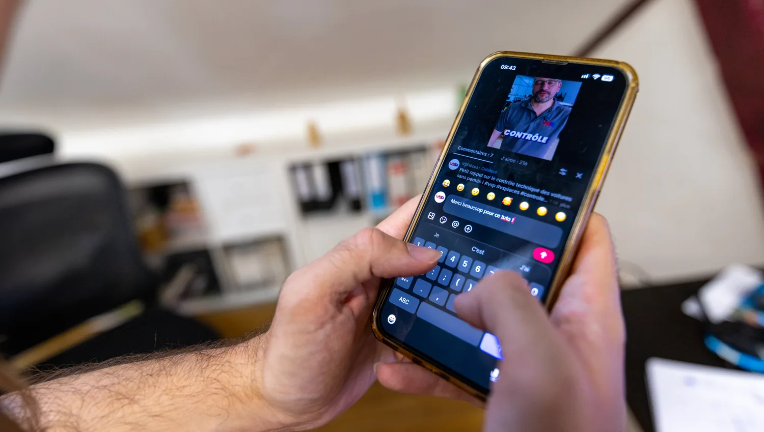 Deux mains rédigent une publication pour les réseaux sociaux sur un téléphone, dans les bureaux de l'agence.