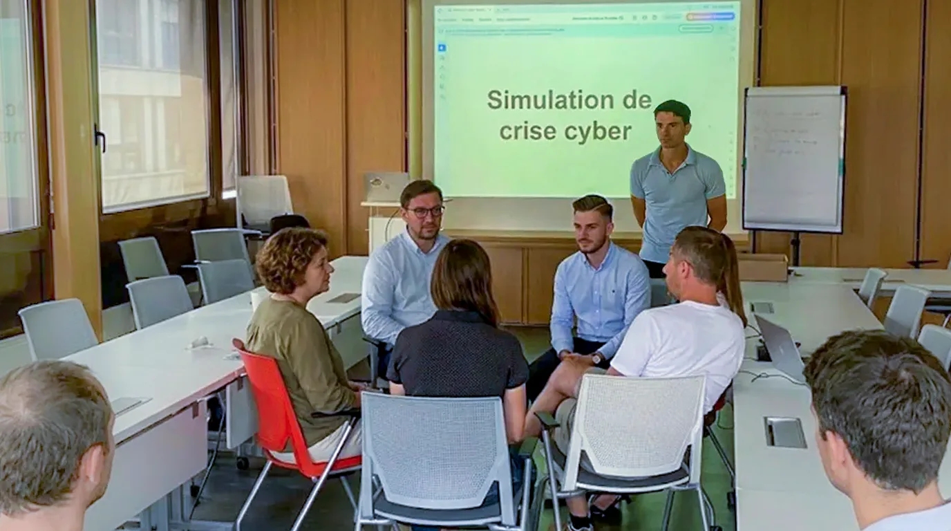 Une simulation de crise cyber animée devant un petit groupe, l'intitulé de l'exercice projeté à l'écran.